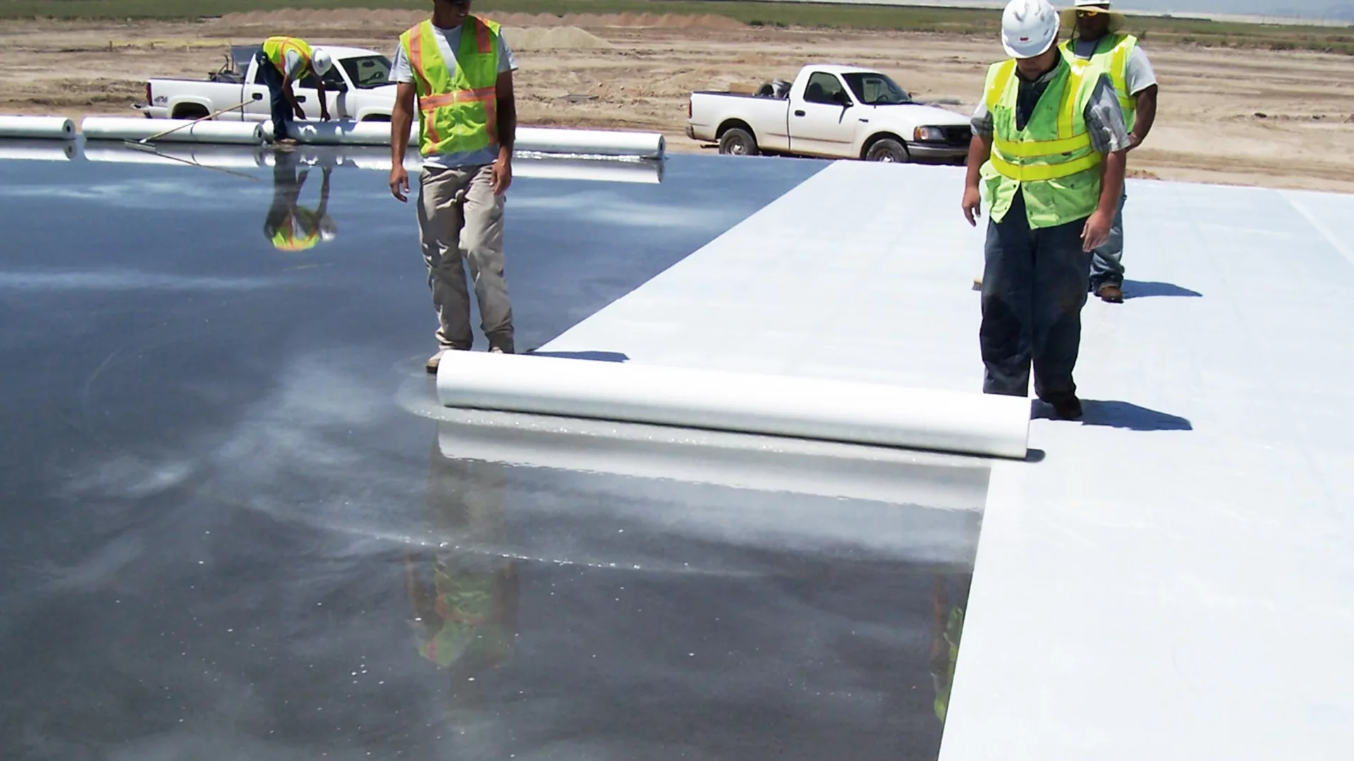 Construction workers curing concrete using a curing sheet